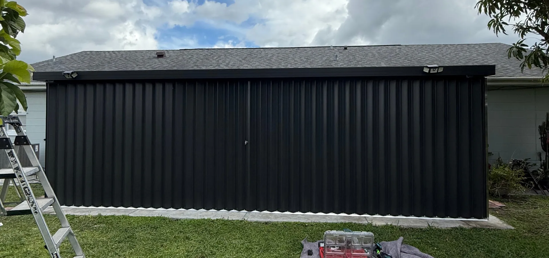 A wide custom accordion shutter enclosure closed across the full length of a covered patio opening
