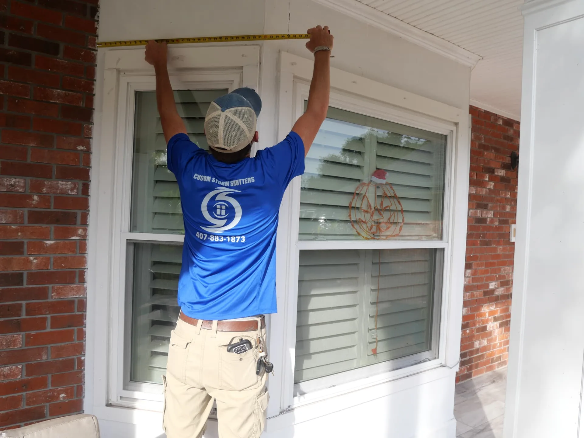 Custom Storm Protection team member measuring the width of a front window with a tape measure