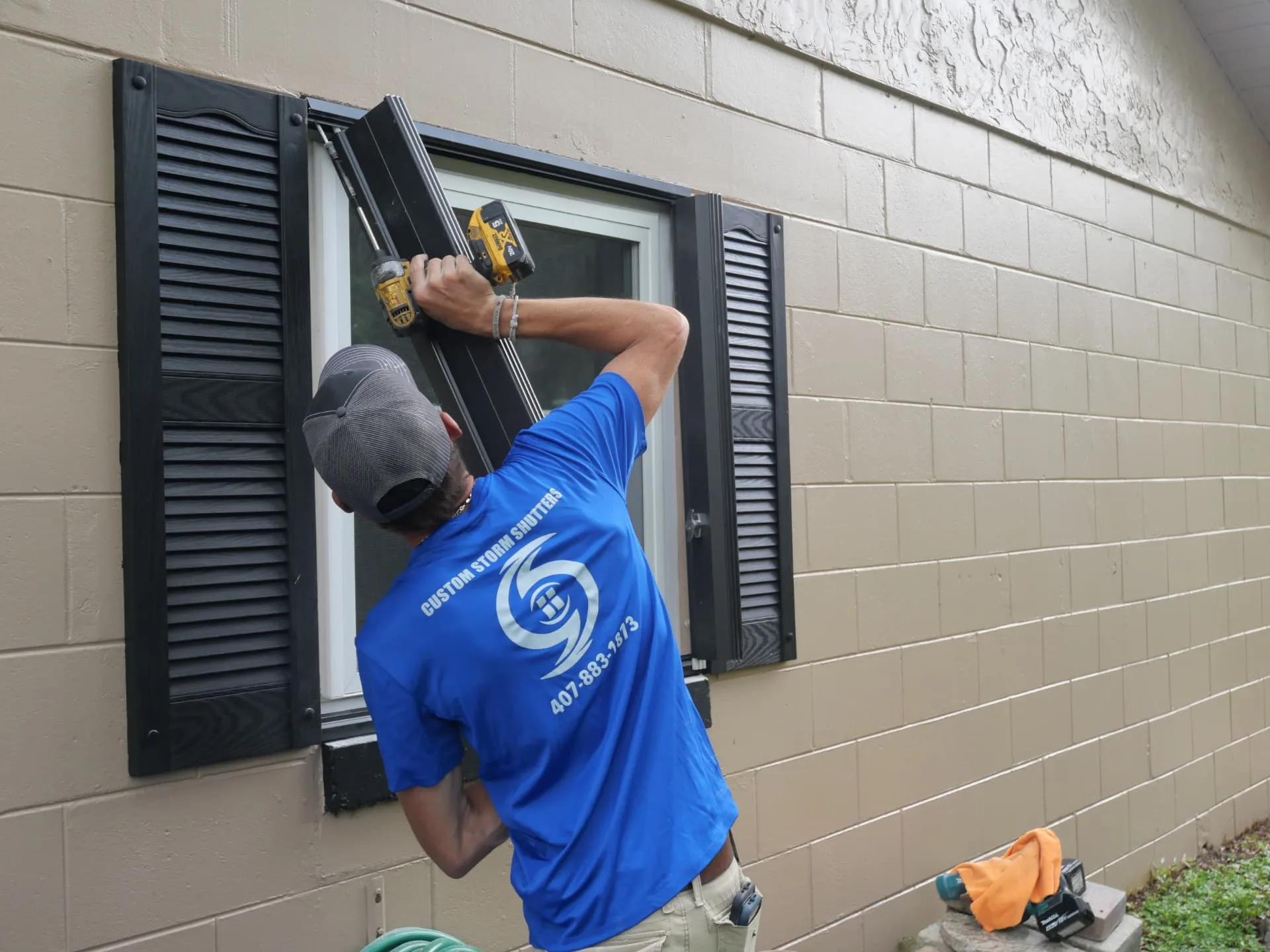 Custom Storm Protection technician securing a shutter track at a window during a repair visit