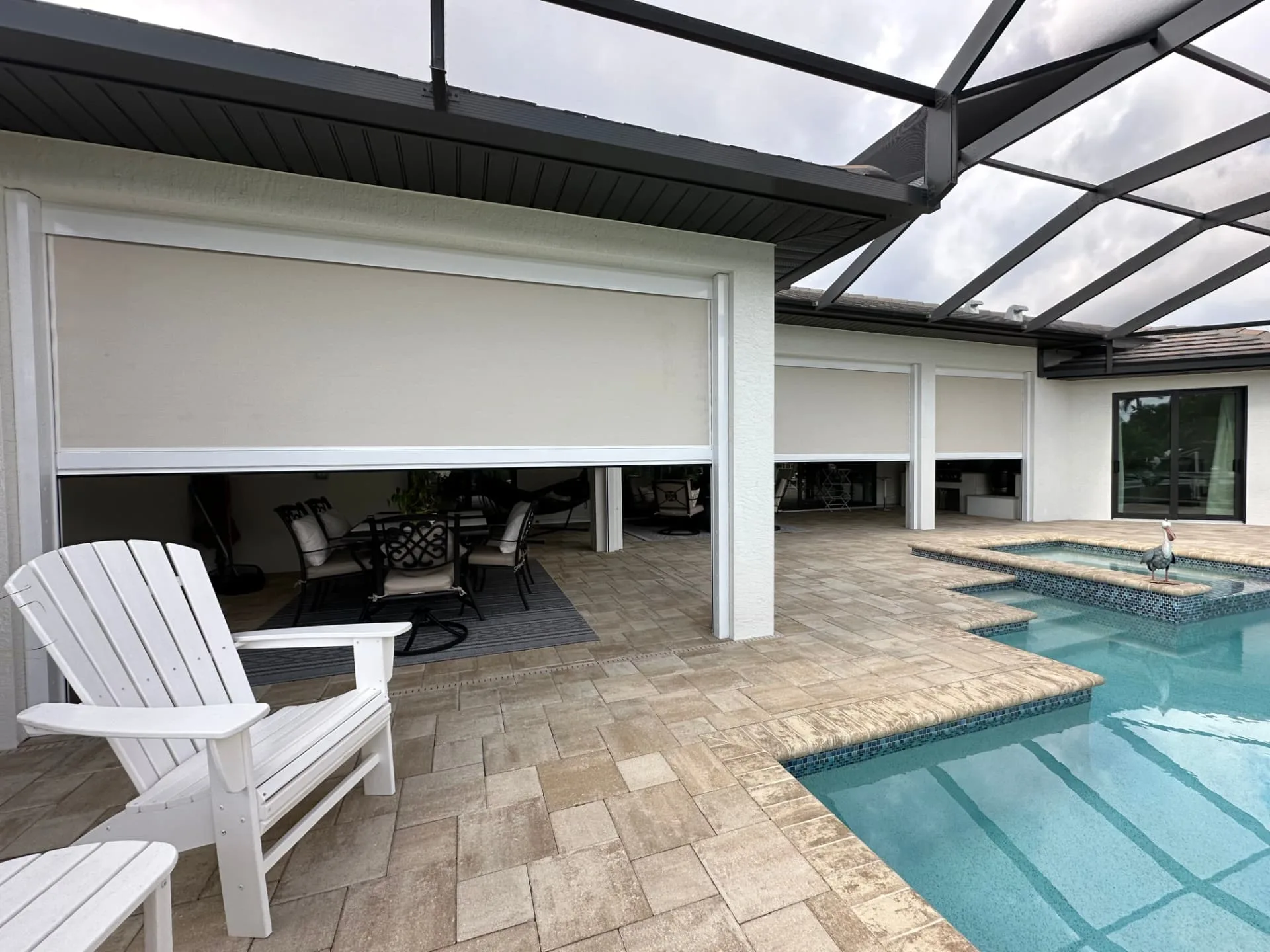 White hurricane screens lowered across a covered lanai beside a screened pool
